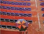  ??  ?? [PHOTO BY IAN MAULE, TULSA WORLD] A lone, hopeful Oklahoma State fan sits under an umbrella on Thursday at ONEOK Field in Tulsa. The Bedlam game between the Cowboys and Oklahoma Sooners was postponed due to rain. The teams are scheduled to play a...