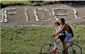  ?? — AFP ?? Teenagers ride a bicycle past the name of late Cuban leader Fidel Castro in Santiago de Cuba province, Cuba, on Friday.