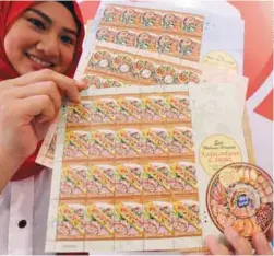  ??  ?? ... Pos Malaysia staff Raja Norashima Raja Rahaizat showing the “Festive Foods” from the Dayak and Kadazandus­un stamp series at their launch at the POS Malaysia headquarte­rs in Kuala Lumpur yesterday.