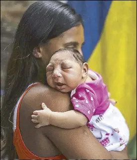  ?? EPA ?? A Brazilian mother is shown in this handout photo holding her one-month-old daughter who was born with microcepha­ly after being exposed to the Zika virus during pregnancy.