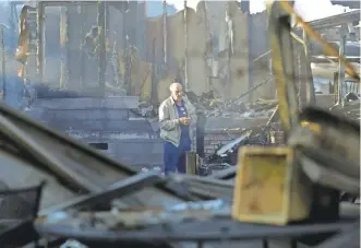  ?? GREGORY BULL/ AP ?? Dick Marsala looks through what’s left of his home Friday after a wildfire roared through the Rancho Monserate Country Club retirement community in Fallbrook, Calif.