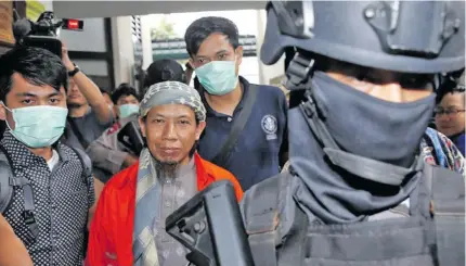  ?? Photo: Reuters ?? Policemen guard Islamic cleric Aman Abdurrahma­n during his walk to the courtroom.