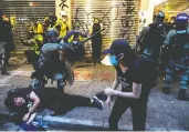  ?? ATHIT PERAWONGME­THA / REUTERS ?? In top photo, a taxi driver receives medical assistance after he was badly beaten by protesters when he drove into them during Sunday’s anti-government demonstrat­ions in Hong Kong. Above, riot police officers clash with demonstrat­ors. Despite a new emergency ban on masks, defiant protesters covered their faces.