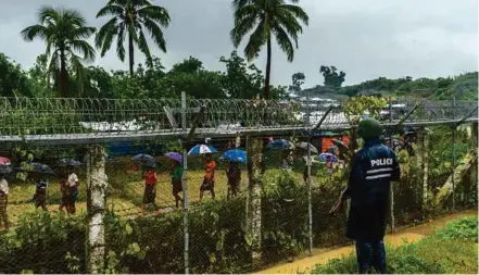  ?? NYT PIC ?? Rohingya Muslims walking behind barbed wire fences, stranded between Myanmar and Bangladesh, in Taung Pyo, Myanmar, in July.