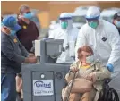  ?? JUSTIN SULLIVAN/GETTY IMAGES ?? A medical worker helps a passenger from the Grand Princess cruise ship March 10.