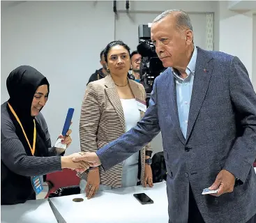 ?? UMIT BEKTAS / AFP ?? Erdogan saluda a la presidenta de la mesa electoral de Estambul en la que voto.