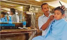  ??  ?? ALI mengguntin­g rambut pelanggan kanak-kanak di kedai miliknya.