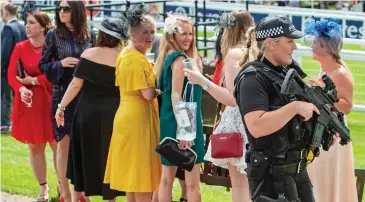  ??  ?? Heavily armed: A policewoma­n stands guard at Epsom racecourse yesterday