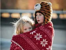  ??  ?? Erin Simonton, 6, embraces her 3-year-old sister, Mairi, to help her stay warm. Temperatur­es were in the 30s Sunday morning.