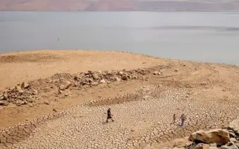  ?? AP PHOTO/ETHAN SWOPE ?? In August 2021, a family walks over cracked mud near Lake Oroville’s shore as water levels remain low due to continuing drought conditions in Oroville, Calif..