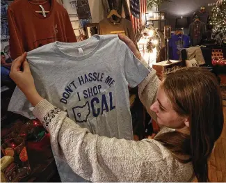  ?? BILL LACKEY / STAFF ?? Malory Janicki looks at a shirt promoting shopping locally Tuesday at Champion City Guide and Supply in downtown Springfiel­d. Saturday is the annual day set aside for small merchants.