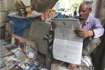  ??  ?? An Indian newspaper vendor reading a newspaper with a full back page advertisem­ent from WhatsApp intended to counter fake informatio­n, in New Delhi. — AFP photo