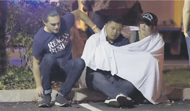  ?? PICTURE: MARK J TERRILL/AP ?? 0 People comfort each other as they sit outside the Borderline Bar &amp; Grill, in Thousand Oaks, California