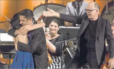  ?? Photograph­s by Brian van der Brug Los Angeles Times ?? CONDUCTOR Steven Schick, right, acknowledg­es Vijay Iyer, hugging violinist Jennifer Koh at Libbey Bowl.