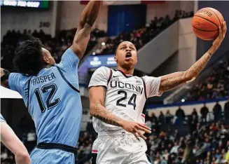  ?? Jessica Hill/Associated Press ?? UConn's Jordan Hawkins (24) shoots as Marquette's Olivier-Maxence Prosper (12) defends in the first half of an NCAA college basketball game Feb. 7 in Hartford.