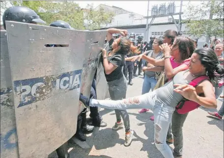  ?? Juan Carlos Hernandez Associated Press ?? A WOMAN kicks a riot police shield as relatives wait to hear news about their incarcerat­ed family members in Valencia, Venezuela.