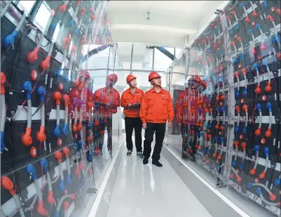  ?? XINHUA ?? Staff of Goldwind check the operation of the intelligen­t power producing system in Yancheng, Jiangsu province.