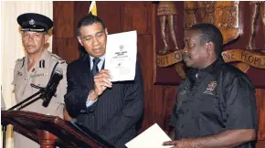  ?? NORMAN GRINDLEY/CHIEF PHOTO EDITOR ?? Prime Minister Andrew Holness (centre) shows the media a copy of the gazette as he declares a state of public emergency in the St Catherine North Police Division during a press conference at Jamaica House yesterday. Also in picture are Rober t Montague...