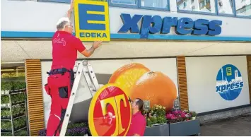  ?? Fotos: Edeka Südbayern ?? Das T weicht dem E: Arbeiter tauschen das alte Tengelmann Schild gegen das Edeka Xpress Logo aus. Die neuen Xpress Läden sind sozusagen Edeka Filialen im Kleinforma­t.