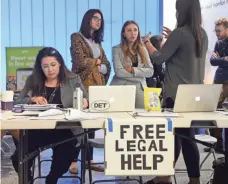  ?? STEPHEN CARR, AP ?? Immigratio­n attorney Maggie Castillo, left, of the American Immigratio­n Lawyers Associatio­n, offers her services to travelers affected by President Trump’s travel ban at Los Angeles Internatio­nal Airport on June 29, 2017.