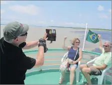  ?? PETER PRENGAMAN, AP ?? Tourists take a picture of the so-called “meeting of the rivers” outside Manaus, Brazil. In this area, the Rio Negro and the Rio Solimoes combine, keeping their own colours for miles.