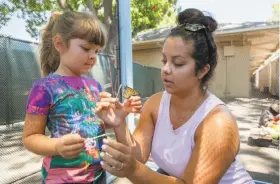  ?? Brittany Hosea-Small / Special to The Chronicle ?? Sarah Rodrigues shows daughter Adellyn Rodrigues, 4, a small butterfly at the Sky River Butterflie­s tent at the Alameda County Fair.