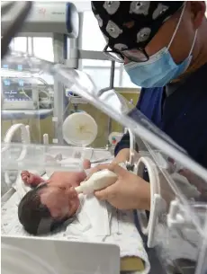  ?? — AFP file photo ?? A medical staff member feeding a newborn baby in the paediatric ward of a hospital in Fuyang in China’s eastern Anhui province.