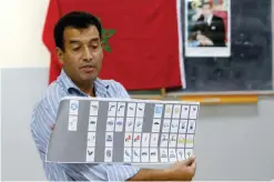  ??  ?? RABAT: The president of a polling station shows a ballot as officials and political party’s representa­tives count the ballots in the polling station on Friday. — AP