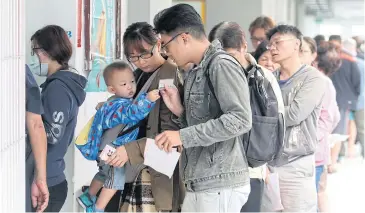  ??  ?? READY TO CHOOSE: People line up at a ballot station to vote for city mayor in Kaohsiung, Taiwan yesterday.