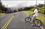  ?? MARCO GARCIA / AP ?? Leilani Estates resident Sam Knox watches lava stretch across the road Saturday in Pahoa, Hawaii. Knox’s home is less than a few hundred yards from the lava flow and he does not have any plans to evacuate.