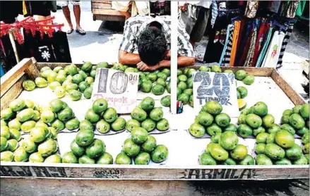  ??  ?? A man selling mangoes rests on his wooden cart at the Avenida market in Manila.