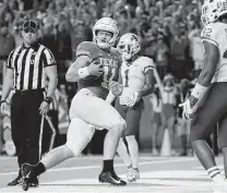  ?? Tim Warner / Getty Images ?? Sam Ehlinger rushes for a touchdown in the first half, but he sat in the second half after re-aggravatin­g a shoulder injury.