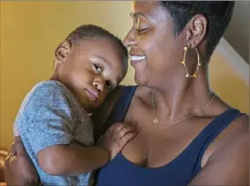  ?? Steve Mellon/Post-Gazette ?? Tamaira Binion, 37, holds her son, Jann Council Jr., 2, at the family's Hill District home. Ms. Binion and her husband, Jan Council Sr., plan on easing their son back into day care at Hug Me Tight Childlife Center, which is reopening after weeks of closure because of COVID-19.