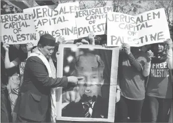  ?? AP PHOTO ?? A Muslim protester plays with a portrait of U.S. President Donald Trump with horns and fangs as they try to march toward the Israel Embassy to protest against Trump’s decision to recognize Jerusalem as the capital of Israel in metropolit­an Manila.