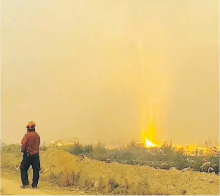  ??  ?? A B.C. Wildfire Service crew member encounters a fire whirl near Vanderhoof on Aug. 19.