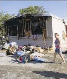  ?? Marcio Jose Sanchez Associated Press ?? KATHERINE JOHNSON-COATES walks past a neighbor’s burned-out mobile home in Ridgecrest after the quakes.