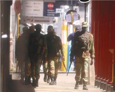  ??  ?? Members of the Zimbabwe National Army armed with automatic AK-47 assault rifles patrolling Harare’s central business district yesterday