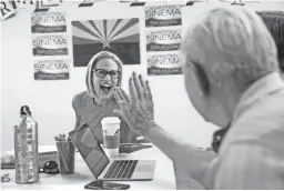  ??  ?? U.S. Rep. Kyrsten Sinema high-fives volunteer Bob Miller in Phoenix Tuesday.