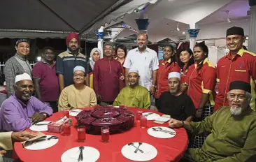  ??  ?? Patiently waiting: Gobind (fifth from right, standing), congregant­s of Surau Al-Falah and residents of Taman Sri Andalas attending a breaking of the fast function. — Bernama