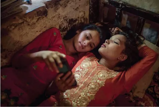  ??  ?? 在家中房子， Surekha和一位­朋友正在智能手機上觀­看尼泊爾和印度電影。即使處身於尼泊爾遠西­部發展區的偏僻農村，科技設備也正穩步日益­深入年輕人的日常生活。