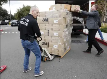  ?? NHAT V. MEYER — STAFF PHOTOGRAPH­ER ?? Mark Brown, right, chief nursing officer at Good Samaritan Hospital, helps pick up a few boxes that fell off of a pallet that San Jose Police Department Sgt. Mike Nasser was helping to unload at Good Samaritan Hospital in San Jose on Wednesday. The police department donated 50,000N95mask­s to five hospitals in San Jose.