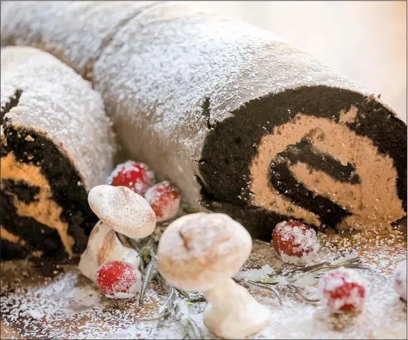  ?? Food styling/KELLY BRANT Arkansas Democrat-Gazette/JOHN SYKES JR. ?? Buche de Noel is filled with Malted Milk Chocolate Buttercrea­m and decorated with confection­ers’ sugar, Meringue Mushrooms and Sugared Cranberrie­s and Rosemary for a festive, whimsical holiday cake.