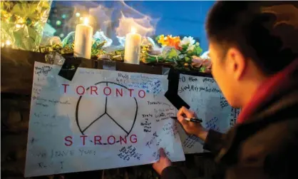  ?? Photograph: Geoff Robins/ AFP/Getty Images ?? A mourner writes a message during a vigil near the site of the van attack in Toronto, Canada, on 24 April 2018.