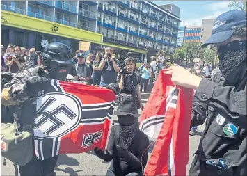  ?? MANUEL VALDES — THE ASSOCIATED PRESS ?? Counterpro­testers tear a Nazi flag Saturday. Small scuffles broke out during protests, but there were no major clashes.