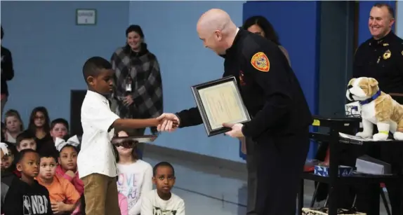  ?? COURTESY ROCKLAND PUBLIC SCHOOLS ?? QUICK THINKING: Rockland fire Chief Scott Duffey congratula­tes R. Stewart Esten Elementary School fourth-grader Joshua Joseph at an assembly Tuesday honoring Joshua for calling 911 after his sister Joanne, 6, shown below left with her brother Wednesday, suffered a seizure at home last month. Below right, Joshua holds awards from the Rockland police and fire department­s.