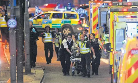  ?? AFP ?? Police officers and emergency workers attend to a person injured in a terror attack on London Bridge on Saturday night.