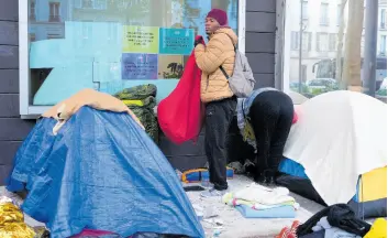  ?? AP ?? A migrant packs his belongings in a makeshift camp in Paris.