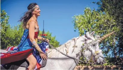  ?? ROBERTO E. ROSALES/JOURNAL ?? Wonder Woman — aka Jennifer Verhoog — rides a unicorn named Smokey down Corrales Road during the village’s Fourth of July parade on Thursday.