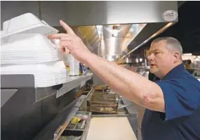  ?? KIM HAIRSTON/BALTIMORE SUN ?? Tom Anuszewski, general manager at Sea King Seafood Market and Pig Picker's BBQ, grabs a foam container as he fills orders. Alternativ­e packaging would add significan­t cost.