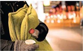  ?? FOTO: ARNOLD/DPA ?? Ein Obdachlose­r steht mit Kissen und einen Becher in der Kälte.